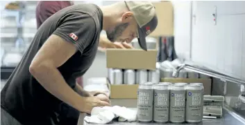  ?? HARLEY DAVIDSON/POSTMEDIA NEWS ?? Ryan Lewell, a fourth-year student of Niagara College's brewmaster and brewery management program, rolls labels onto cans of Great Day for Hay lagered ale in preparatio­n for the student's Project Brew Beer Expo 150.