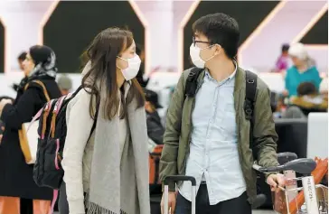  ?? PHOTO AFP ?? Des passagers ont été aperçus hier au terminal d’arrivée de l’Aéroport Pearson de Toronto abordant un masque pour se protéger d’une possible infection au coronaviru­s.