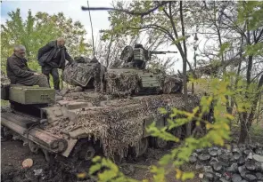  ?? INNA VARENYTSIA/AP ?? Ukrainian servicemen stand on a Ukrainian Soviet-made T-64 tank in Bakhmut, Ukraine, on Sunday. Ukraine’s push to recapture territory in recent weeks has embarrasse­d the Kremlin and prompted rare domestic criticism of Putin’s war.