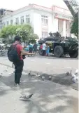  ?? CARMENCITA A. CARILLO ?? A MAN feeds pigeons at the park across the Davao City hall, where an armored infantry fighting vehicle is parked as part of tightened security following the declaratio­n of martial law in Mindanao.