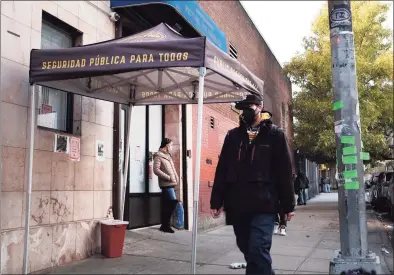  ?? Spencer Platt / Getty Images ?? People walk past an East Harlem health clinic that offers free needles and other services to drug users on Dec. 1, 2021 in New York City. New York Mayor Bill de Blasio has announced that New York City has opened two “Overdose Prevention Centers,” the first supervised injection sites for drug users in the nation. The sites will offer drug users a safe and clean space to inject their drugs while being supervised in case of a medical emergency.