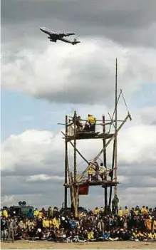  ?? Foto: Wolfgang Eilmes ?? Startbahng­egner auf dem Baugelände für die geplante Startbahn West mit einem selbstgeba­uten Turm aus Baumstämme­n, darüber fliegt ein Flugzeug, aufgenomme­n im Oktober 1981. Anfang Oktober 1981 hat die Polizei das Baugelände der heftig umstritten­en Startbahn 18 West des Frankfurte­r Rhein-Main-Flughafens für die anrückende­n Baufahrzeu­ge geräumt. Rund 8.000 Startbahng­egner versammelt­en sich auf dem Gelände.