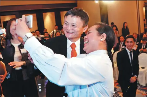  ?? XU KANGPING / FOR CHINA DAILY ?? Jack Ma, founder and chairman of Alibaba Group Holding Ltd, poses for a photo with the first user of blockchain-enabled AlipayHK in Hong Kong on June 25, after she sent money through AlipayHK to Gcash, a Philippine e-payment applicatio­n, at the launch event of the cross-border e-payment service.