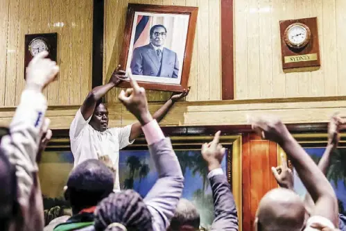  ??  ?? People remove the portrait of former Zimbabwean President Robert Mugabe after his resignatio­n