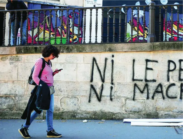  ?? ?? Una joven pasa por una calle de Saint Denis con un grafiti en la pared donde se lee «Ni Le Pen ni Macron»