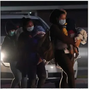  ?? More photos at arkansason­line.com/325biden/. (AP/Julio Cortez) ?? Migrant women carry children through an intake area early Wednesday after crossing the U.S.-Mexico border and surrenderi­ng to authoritie­s in Roma, Texas.