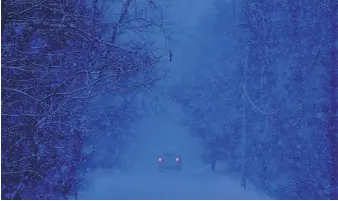  ?? ROBERT BUKATY/ASSOCIATED PRESS ?? A car can barely be seen as it drives through Durham, Maine, on Thursday during a fierce nor’easter that left tens of thousands of residents without power.