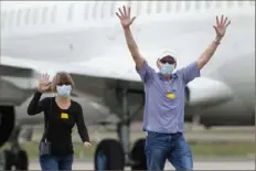  ?? Jeff Chiu/Associated Press ?? Passengers from the Grand Princess, a cruise ship carrying multiple people who have tested positive for COVID-19, gesture toward reporters while walking on the tarmac before boarding a plane Tuesday in Oakland, Calif. The passengers on the flight are going to be quarantine­d at Lackland Air Force Base in San Antonio.