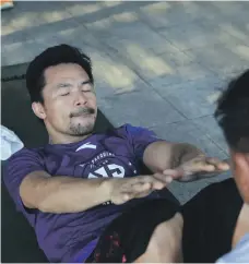  ?? Jake Versoza for The National ?? Left, Manny Pacquiao speaks to fans at a gym in the heart of Manila; Above, there is no time to waste as he does abdominal exercises in the driveway of his house