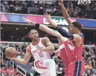  ?? AP ?? Eric Gordon (10), de los Rockets, pasa la pelota mientras es defendido por Marcin Gortat (13) y Otto Porter Jr. (22), de los Wizards, durante la primera mitad del partido de anoche en el baloncesto de la NBA.