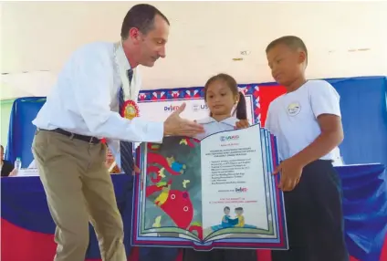  ?? SUNSTAR FOTO / ALLAN CUIZON ?? PROMOTING LITERACY. USAID Philippine­s Director Brian Levey joins pupils in the turnover of the Basa Pilipinas Project.