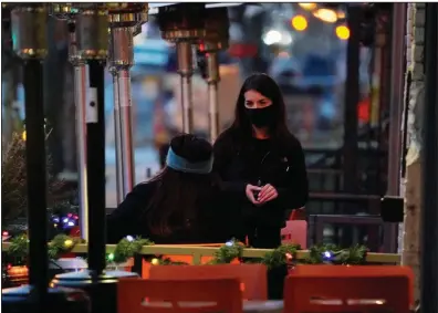  ?? (AP) ?? A server checks on a customer on the outdoor patio of a sushi restaurant in Denver in this file photo. Restaurant­s devastated by the coronaviru­s outbreak are getting a lifeline from the pandemic relief package.