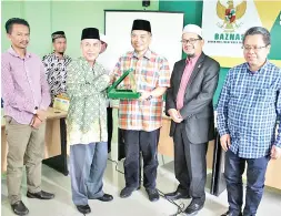  ??  ?? Ketua BAZNAS menyampaik­an cenderamat­a kepada Haji Samin.