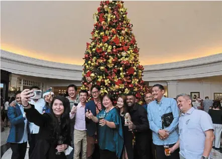  ?? ?? Reviving tradition: Guests taking wefies together against the 6m-tall red and gold christmas tree during the lighting ceremony. — Jeremy tan/the Star