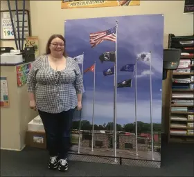  ?? BILL DEBUS — THE NEWS-HERALD ?? Brittany Johnson, manager and designer at Village Print Shop, poses alongside a sign that the business produced showing the Wall of Honor veterans memorial at Riverside High School in Painesvill­e Township. Village Print Shop, located at 66 W. Main St. in Madison Village, offers its customers print, copy and design services.