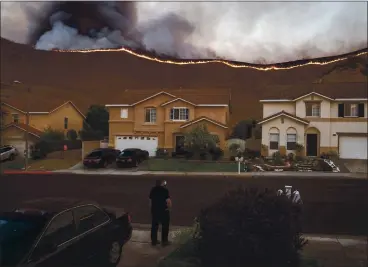  ?? ERIC THAYER — THE NEW YORK TIMES ?? A person surveys the Blue Ridge Fire near residences in Chino Hills in October. The state announced on Thursday that it would prevent insurance companies from dropping at-risk homeowners for one year in many parts of the state.