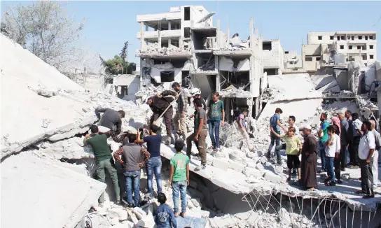  ??  ?? Syrian residents and members of the Syrian Civil Defense, also known as White Helmets, search on Saturday for victims amid the rubble of a building following an airstrike in Idlib province. (AFP)