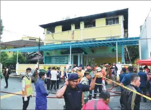  ?? ASSOCIATED PRESS ?? Police and rescue personnel work at a religious school cordoned off after a fire in Kuala Lumpur on Thursday.