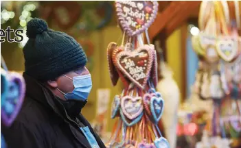  ??  ?? An employee wears a protective mask in front of a sales booth at the drive in Christmas market in Landshut, southern Germany.