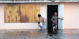  ??  ?? > A couple leave their flooded home in Fort Myers, Florida