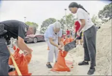  ?? Amy Beth Bennett / South Florida Sun-sentinel via Associated Press ?? Joan Chang, center, gets help filling her bags during a sandbag giveaway in preparatio­n for Hurricane Dorian, Friday in Margate, Fla.