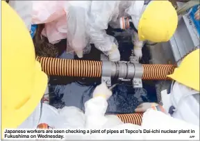  ?? AFP ?? Japanese workers are seen checking a joint of pipes at Tepco’s Dai-ichi nuclear plant in Fukushima on Wednesday.