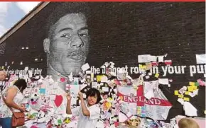  ?? PIC BY ZAHARAH OTHMAN ?? Ehsan with a piece of poetry he wrote in support of Marcus Rashford, in front of the latter’s mural in Withington, Manchester.