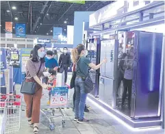  ?? ?? People compare different sizes and styles of refrigerat­ors at an Electrical Appliances Expo.