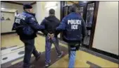  ?? ASSOCIATED PRESS FILE ?? Immigratio­n and Customs Enforcemen­t officers escort an arrestee in an apartment building, in the Bronx borough of New York.