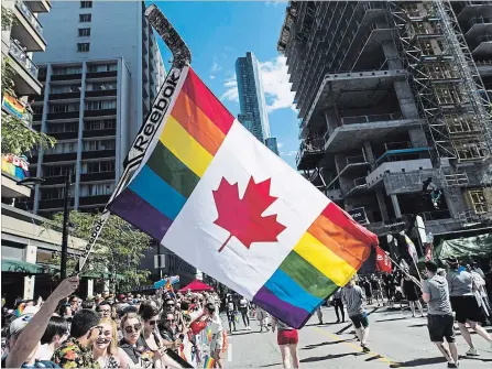  ?? MARK BLINCH THE CANADIAN PRESS ?? A man holds a flag during the Toronto Pride parade, June 2017. The first court challenge to an Alberta law that bars schools from telling parents when their children join gay-straight alliances carries some echoes of the debate over legalizing same-sex...