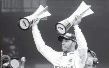  ??  ?? Mercedes driver Lewis Hamilton, of Britain, raises trophies after winning the Brazilian Formula One Grand Prix at the Interlagos race track in Sao Paulo, Brazil. ASSOCIATED PRESS