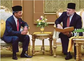  ?? BERNAMA PIC ?? Yang di-Pertuan Agong Sultan Muhammad V reading the Royal Commission of Inquiry’s report on Bank Negara Malaysia’s foreign exchange trading scandal at Istana Negara yesterday. With him is RCI chairman Tan Sri Mohd Sidek Hassan.