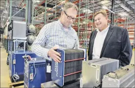  ??  ?? Materials manager Chris Jacobs, left, and company COO Keith Schmid inspect Plug Power’s new metal stack product during the opening. The new Clifton Park site is expected to create 97 jobs,