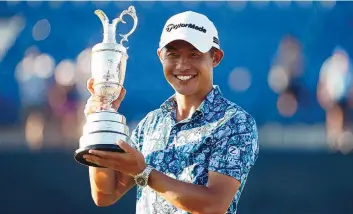  ?? PETER MORRISON/ASSOCIATED PRESS ?? Collin Morikawa holds the claret jug trophy for photograph­ers on the 18th green after winning the British Open Sunday with a tournament-record 265 at Royal St. George’s. Some 32,000 fans were on hand Sunday.