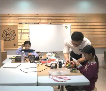  ??  ?? In this picture taken on Mar 2, a teacher instructs children at ‘MG Space’, a small-scale workshop offering digital fabricatio­n, in Shenzhen. Engineers, computer programmer­s and children tinker with self-made radio-controlled toy cars and robotic arms...