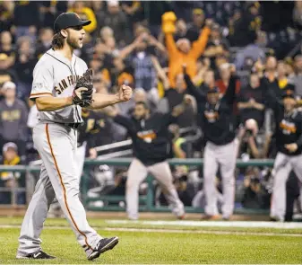  ?? Gene J. Puskar / Associated Press ?? Madison Bumgarner, who pitched a four-hit shutout, starts to celebrate as teammates leave the dugout to join him after the last out against the Pirates in the NL wild-card gameWednes­day.