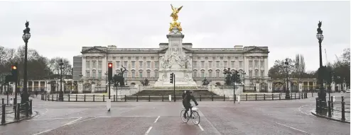  ?? JUSTIN TALLIS / AFP VIA GETTY IMAGES ?? A cyclist rides down the deserted Mall in London, backdroppe­d by Buckingham Palace, as Britain enters a national lockdown on Tuesday.