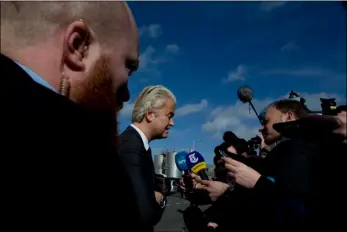  ??  ?? A body guard watches over firebrand anti Islam lawmaker Geert Wilders (center) as he answers questions during an election campaign stop at De Telegraaf newspaper Sunday in Amsterdam, Netherland­s. AP PHOTO