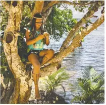  ?? RAPHAEL ALVES/FOR THE WASHINGTON POST ?? Cunhaporan­ga Tatuyo, 22, an Indigenous digital influencer with more than six million Tiktok followers, posts to her profile while perched in a tree in the Amazonian rainforest.