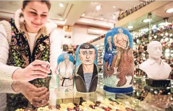  ?? FOTO: AFP ?? Eine Verkäuferi­n arrangiert einige Putin-Fanartikel in ihrem Geschenksh­op.