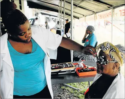  ?? Picture: FEDLIN ADRIAAN ?? HELPING HAND: Phelophepa Health Care Train optometris­t Mbalenhle Msibi assists a patient with an eye test