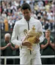  ?? TIM IRELAND — THE ASSOCIATED PRESS ?? Serbia’s Novak Djokovic carries the champion’s trophy after the men’s singles final match of the Wimbledon Tennis Championsh­ips in London, Sunday.