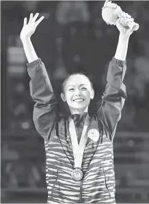  ?? — Gambar Bernama ?? EMAS KELIMA: Amy ceria ketika memberikan ‘pose’ istimewa bersama pingat emasnya pada upacara penyampaia­n pingat di Coomera Indoor Sports Centre, Gold Coast semalam.