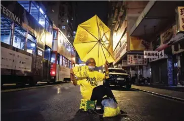  ?? AFP ?? A protester holds up a yellow umbrella as she protests in a street in Hong Kong on Monday. Protesters angry at China’s decision to intervene in the row were subdued by police the day before.