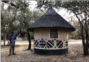  ??  ?? Texan Shaun Thompson stands outside a Ndebele village hut, a lodging upgrade at Big Cave Camp near Matobo National Park in Zimbabwe. Most of the group chose to pitch a tent.