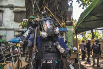  ?? New York Times ?? Ko Soe Win Naing, 26, prepares for war with a GoPro camera on his helmet, a balaclava over his head, tear gas, a sword and a gas mask. His weapon of choice is a fireworks launcher.