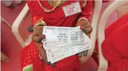  ??  ?? AHMEDABAD: An Indian bride poses for a photograph holding 2500 INR in cash, given as a mandatory ‘mahr’ payment by the groom’s family to the bride at the time of marriage, and which legally becomes her property, a mass wedding ceremony in Ahmedabad. — AFP