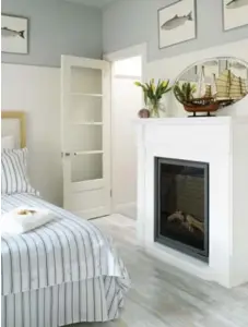  ?? YVONNE DUIVENVOOR­DEN PHOTOS ?? Crisp blue and white bedding and prints of fish echo the nautical theme that drove the design. A small electric fireplace brings warmth to the room.