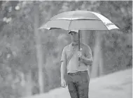  ?? [ADAM CAIRNS/DISPATCH] ?? As rain begins to fall, Jon Rahm holds an umbrella while preparing for his next shot during the final round of the Memorial Tournament on Sunday. Rahm said one of his grandmothe­rs and a great aunt died recently.