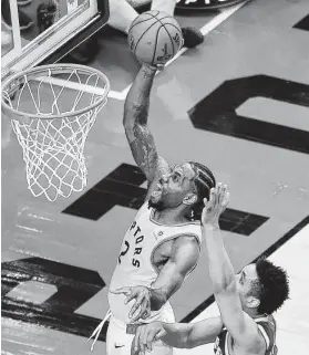  ?? Frank Gunn / Associated Press ?? Toronto’s Kawhi Leonard scores over Milwaukee’s Malcolm Brogdon during the second overtime period of Game 3 for two of his 36 points.